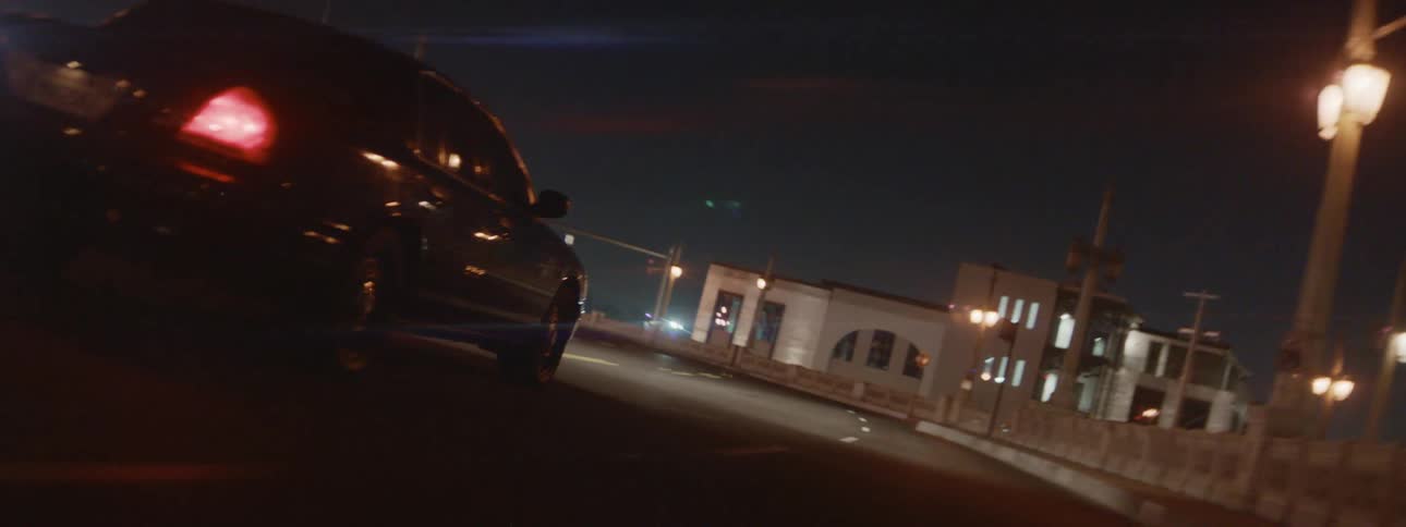 A black car traveling on an urban street at night