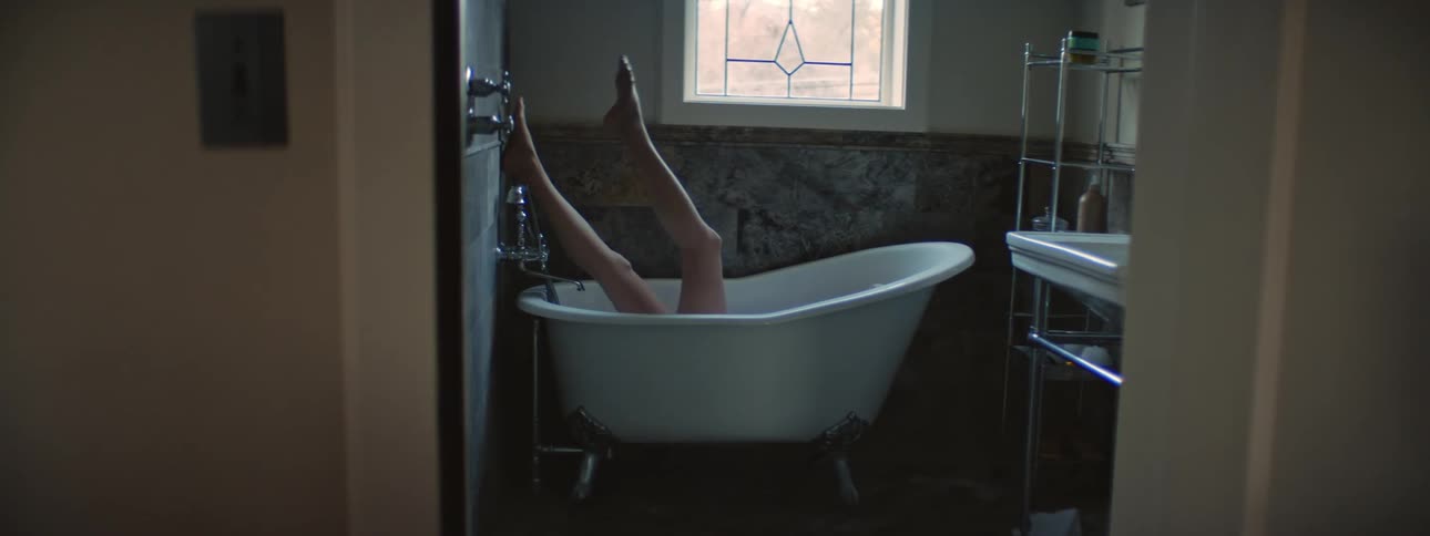 A woman kicking her legs and flapping her arms while lying in an empty bathtub