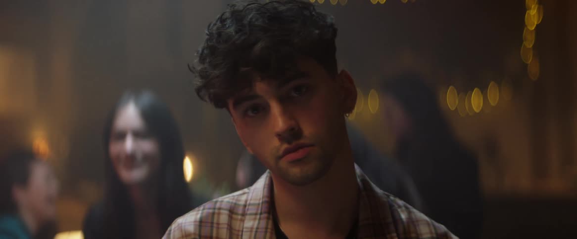 Close up of a man looking directly into the camera with people behind him doing whatever