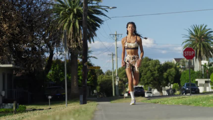 Woman with sports bra shorts and white socks runs on road in the neighborhood