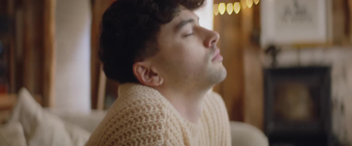 A young man sits deep in thought on his couch
