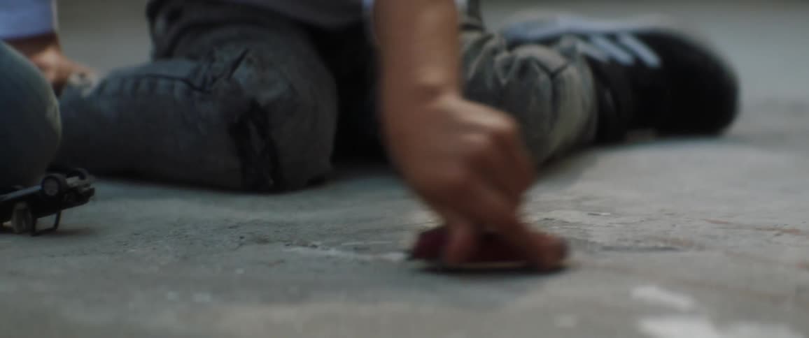 Two children playing with toy cars on the pavement