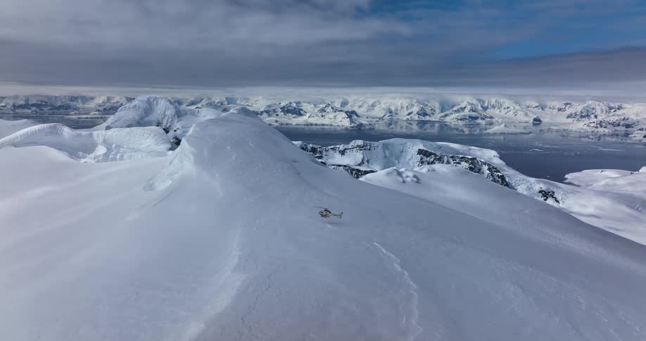 Aerial view of helicopter landing on top of snowy mountains