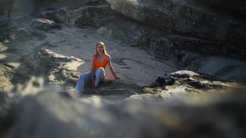 A woman sits on flat rocks in a canyon