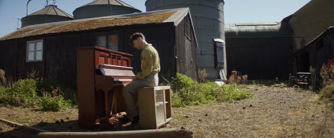 A man is playing a piano in front of the silos