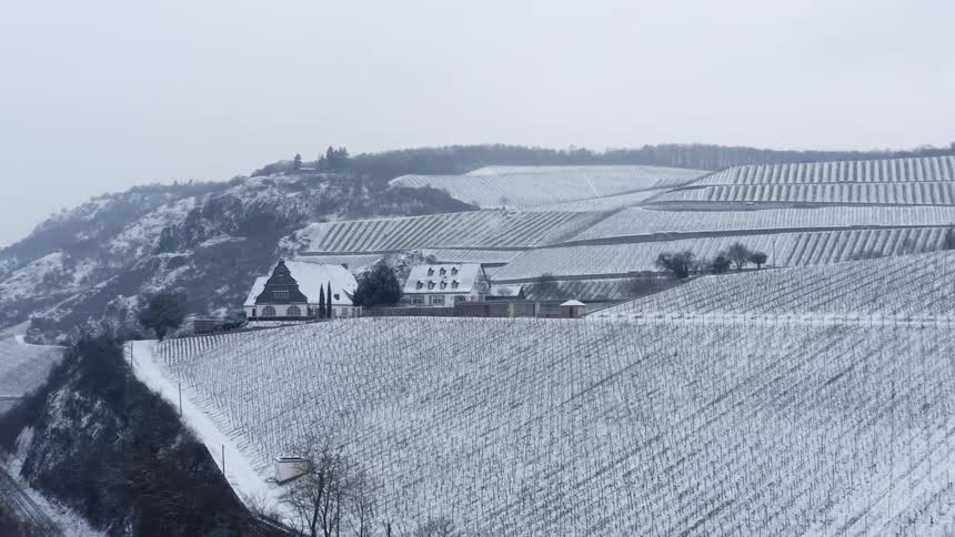 Black and white aerial footage of snow covered crops atop a mountainside