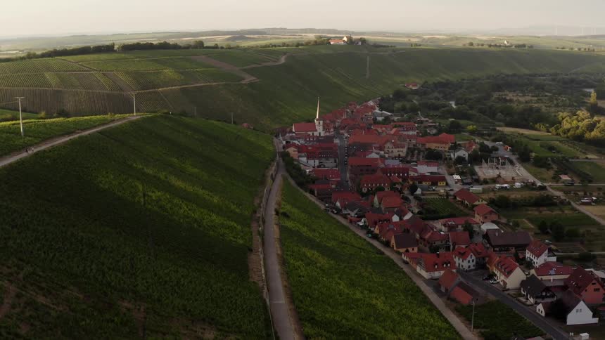 Most of buildings in town near hills including the church have red roofs