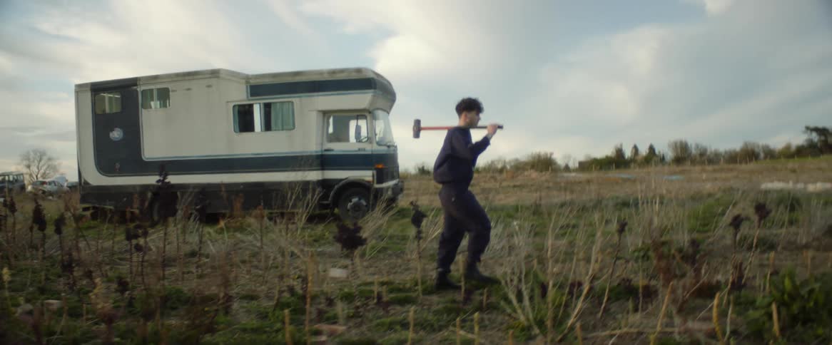 A man is carrying a sledgehammer on the field