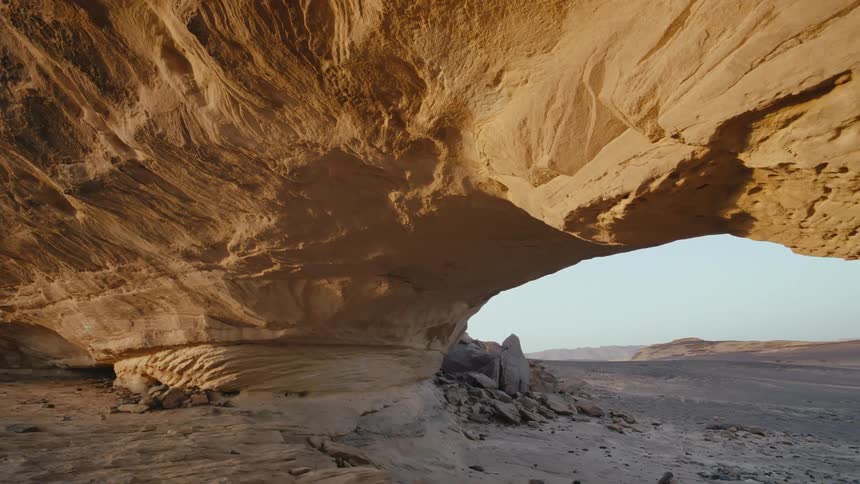 A curved rock formation in a desert forms a natural bridge in Saudi Arabia