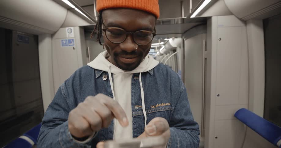 A man scrolls through his phone while standing on a train