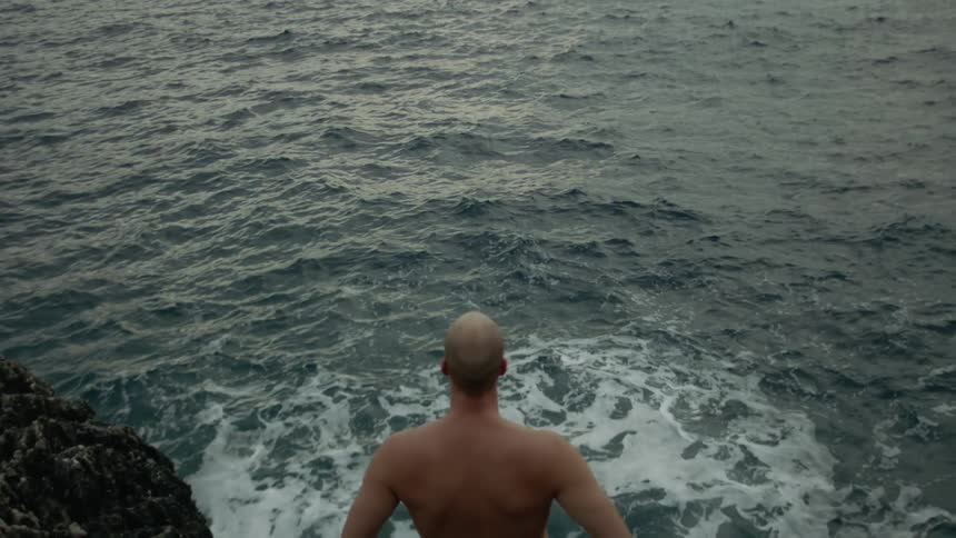 A man is standing in the ocean during the day time