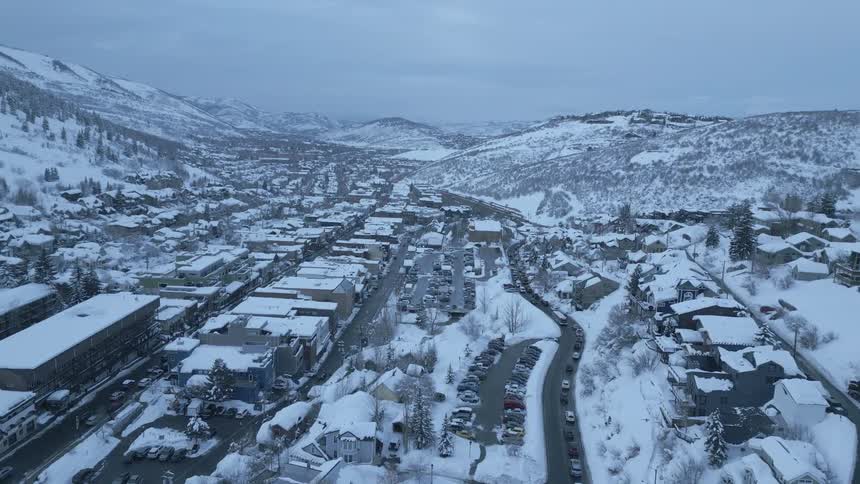 An aerial view of a snowy town in a hilly landscape