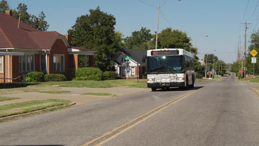 City bus drives along neighborhood street passing intersection