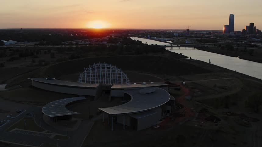 An aerial view of a large structure in a city at sunset