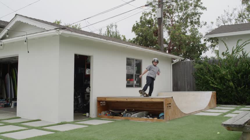 A young boy skateboards on a ramp in his back yard
