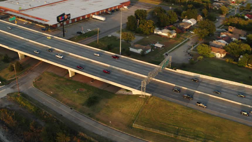 An aerial of a highway going under a bridge with traffic on the road