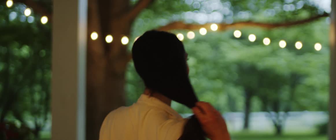 A woman takes her hair out of a ponytail while walking through her house