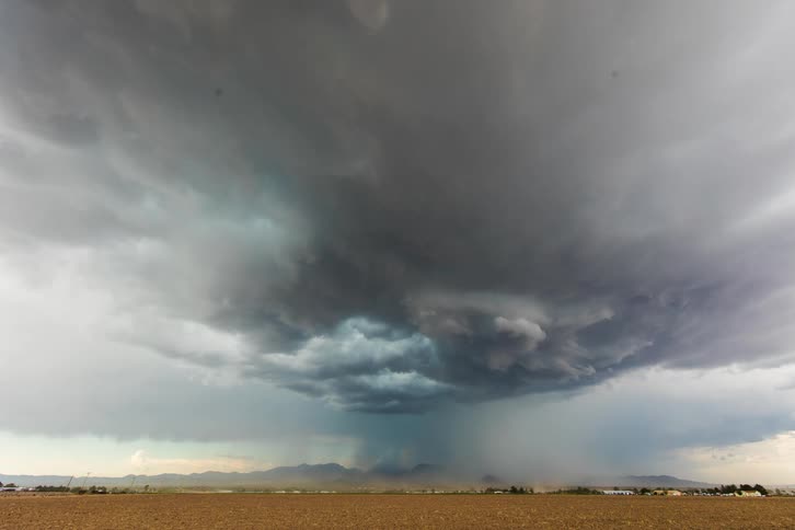 A severe monsoon storm rolling in with large clouds and dust over a flat landscape