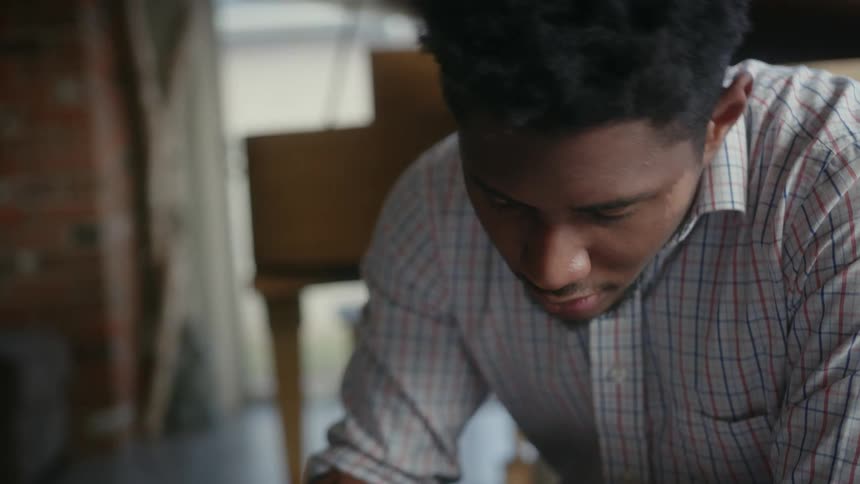 A man is sitting at a table looking down and shaking his head