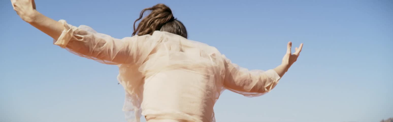 A woman is dancing wildly in the desert spinning and raising her arms in the air as if shes invoking a spirit