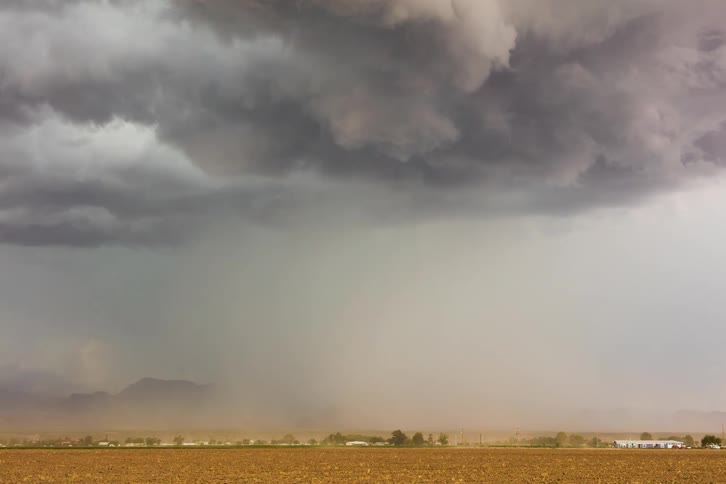 A severe monsoon storm rolling in with large clouds and dust over a flat landscape