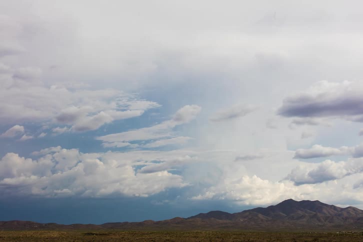 Clouds rolling over mountains and a desert landscape