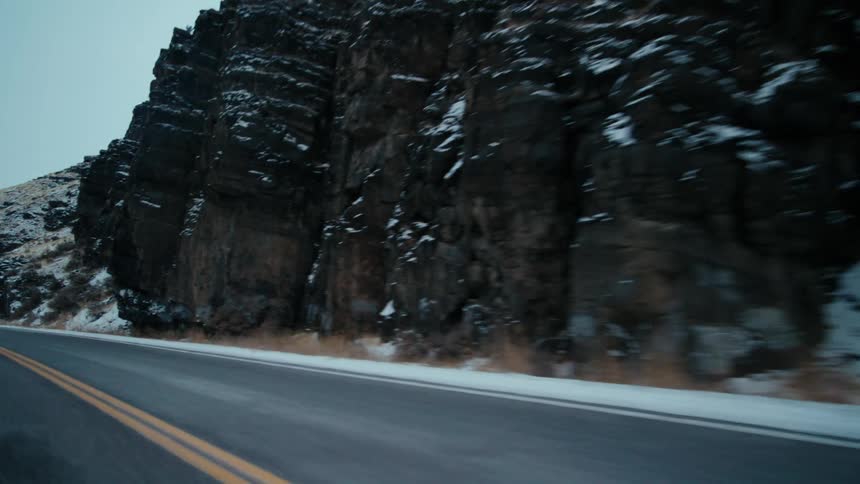 A vehicle drives past a snow capped mountain range