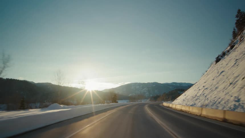 A highway runs past snow covered mountains
