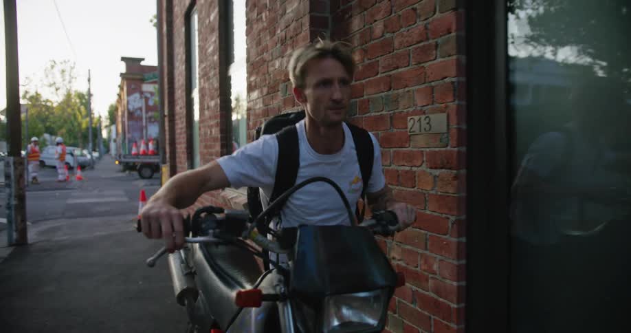Man walking his motorcycle down the street