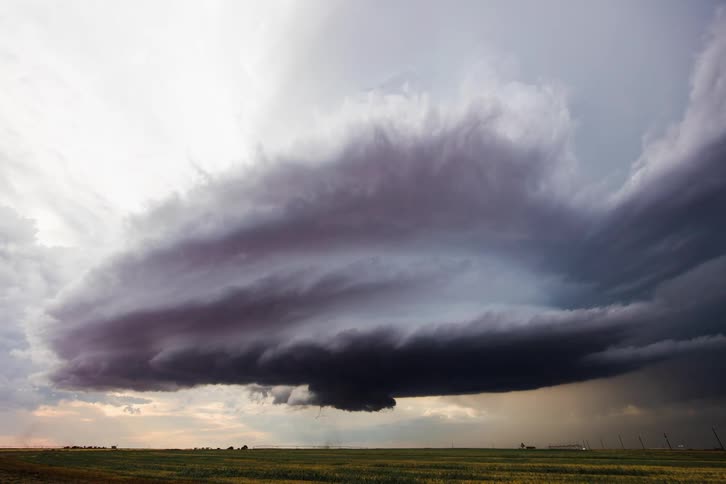 Wide shot of a supercell forming a tornado which touches ground and moves across landscape for a bit