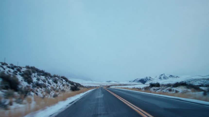 A highway runs past snow covered mountains