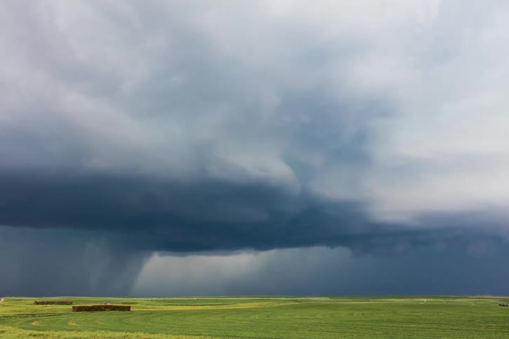 Dark clouds gather over green field