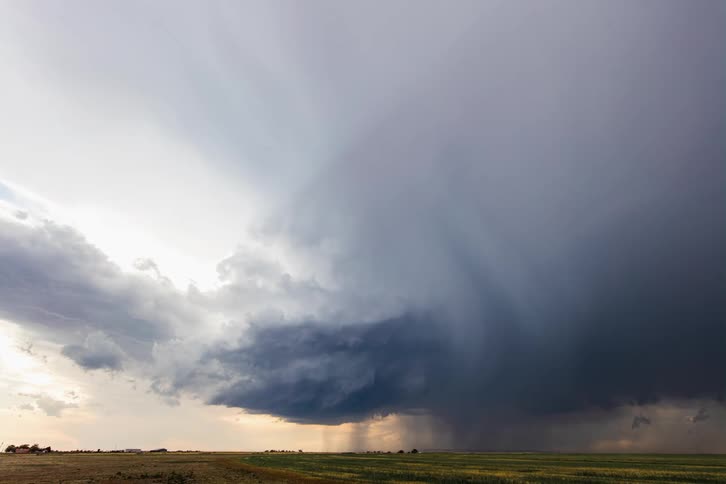 Dark clouds and lighting form over a field