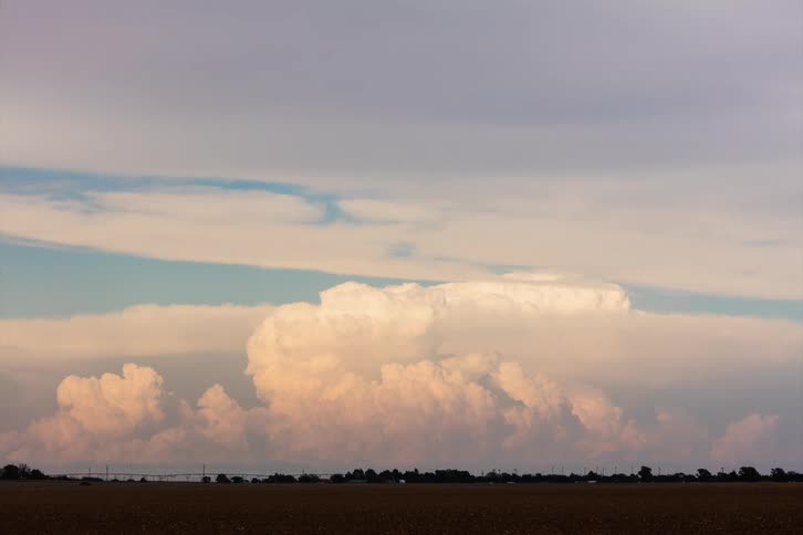 Sunlight shines on fluffy cumulus clouds on the horizon