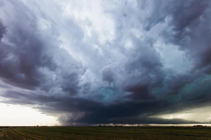 Dark storm clouds float over green field