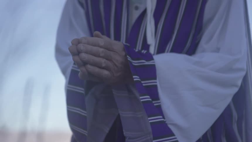 A man holds his hands together in prayer