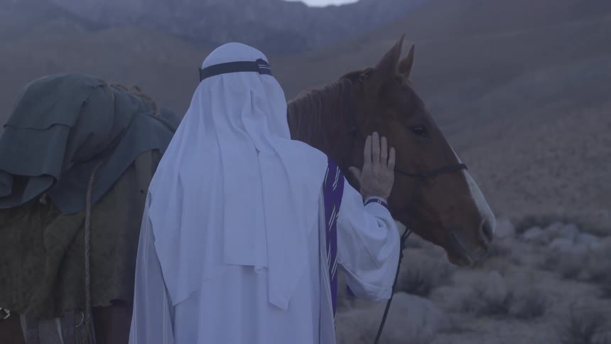 A man pets his horse in the desert