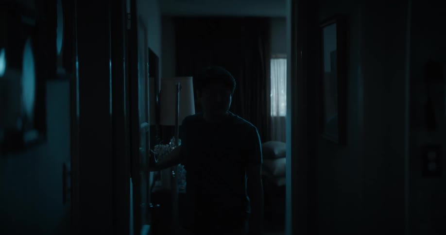 A man walks down the dark hallway