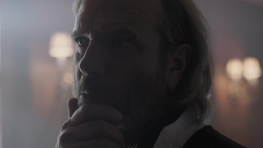 A man is looking at something before putting his hand on his chin