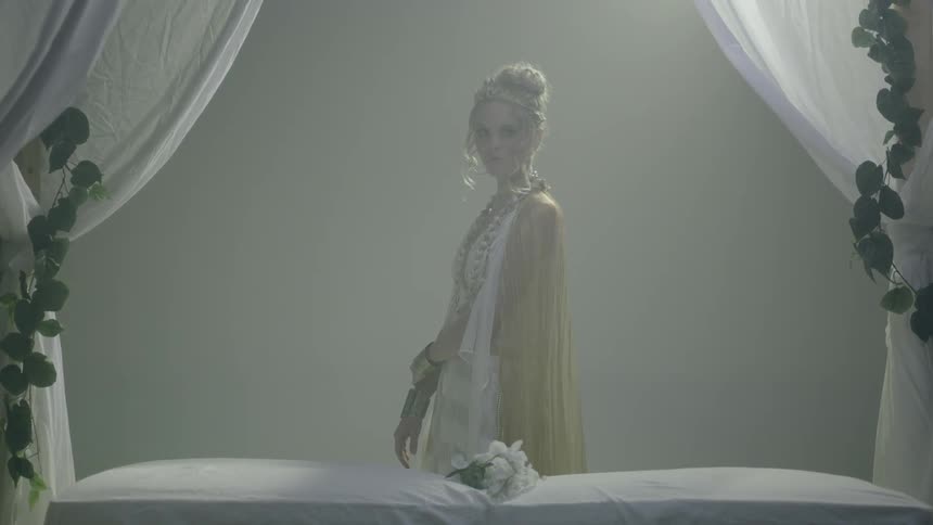 A woman standing next to a canopy bed