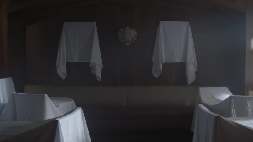 Photos and furniture in this room are covered with sheets