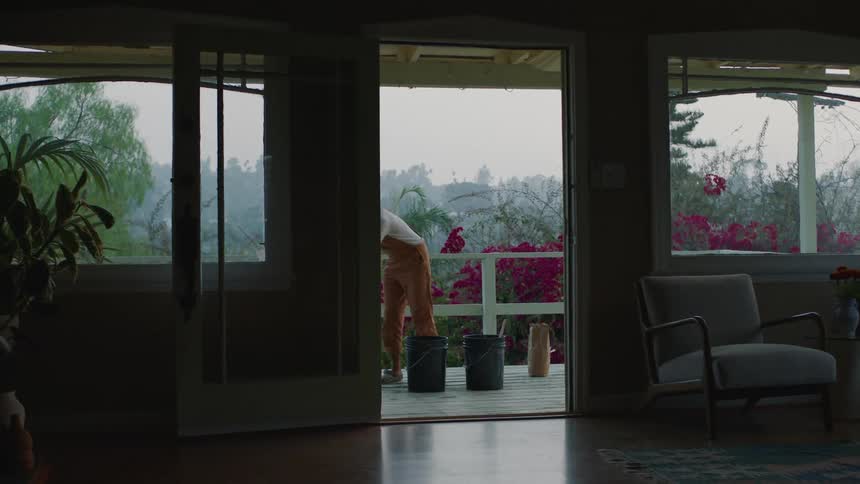 A woman stands on her balcony at home and mixes things in pails