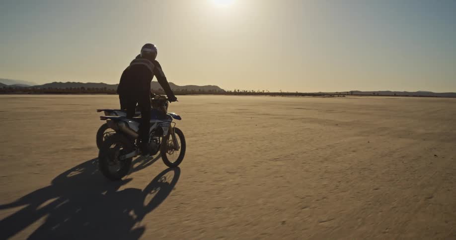 Two men ride motorbikes through the desert