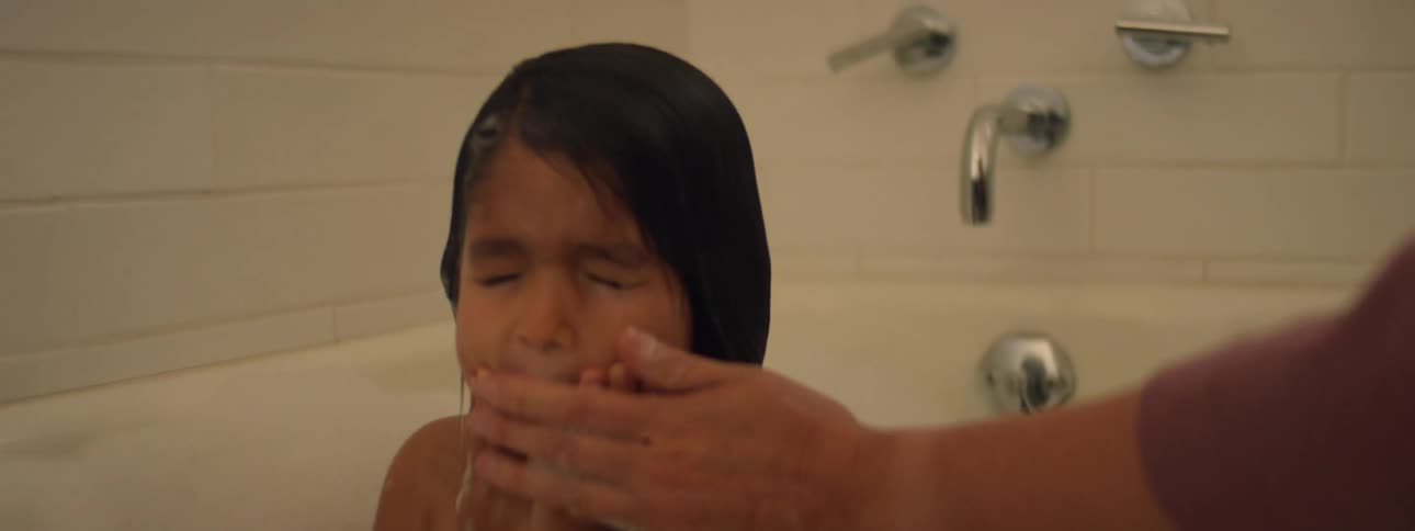 A little girls laughs as her mom helps her bathes and wipes her face