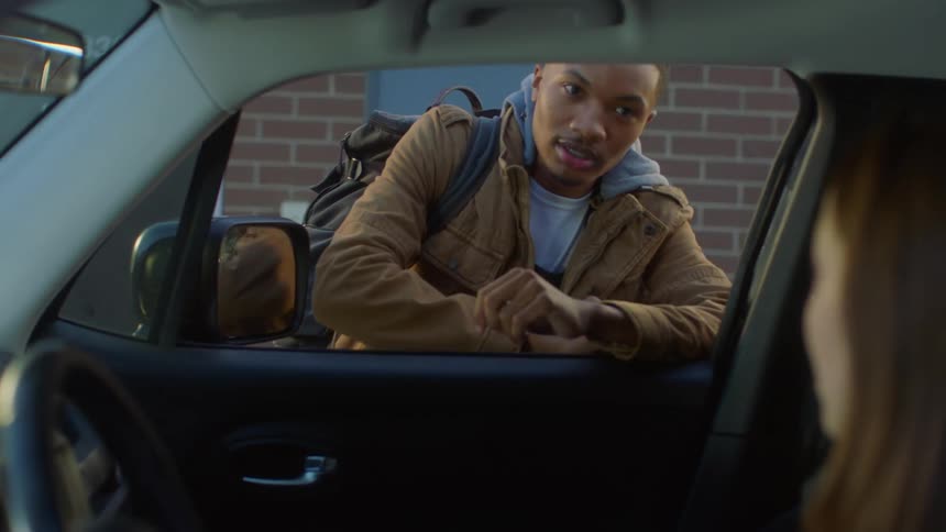A man and woman talking to each other at a car