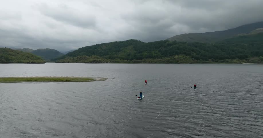 Three people paddle down the water