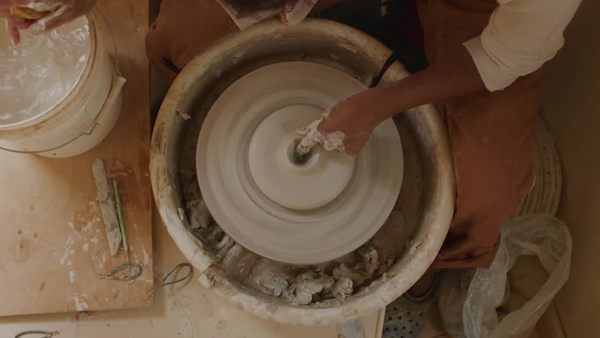A woman makes pottery on a pottery wheel