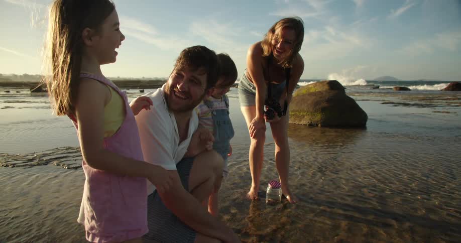 Mother father and two children a boy and a girl are spending the day at the beach collecting sea shells
