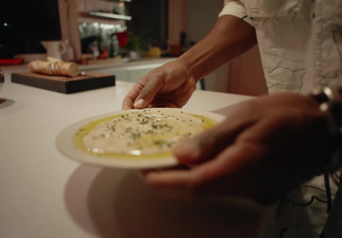 Two men carry plates of food out of their kitchen