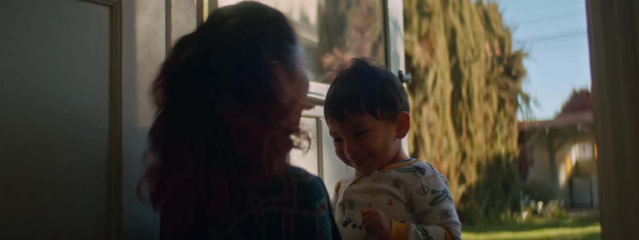 Mother and son touch foreheads and smile while in doorway of home